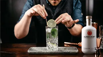 Glass with cocktail is decorated with lime and mint.