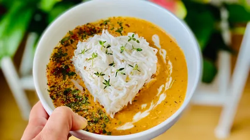 Bowl of rice and sauce, hand-held in an environment.