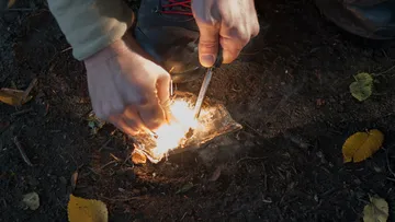 Hands light fires from sparks in the soil.