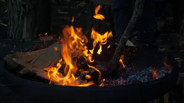 Flammen über Holz, während ein Stock bewegt wird.