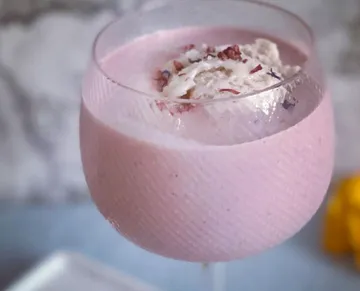 Rosa Getränk in einem Glas mit Sahne und Dekor.