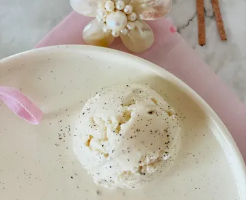 Ice cream scoop on a plate decorated with flowers in the background.