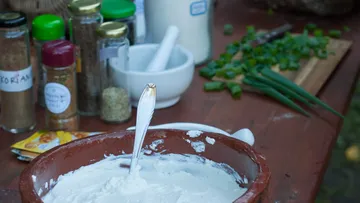 Schüssel mit Creme, umgeben von Kräutern und Gewürzen.
