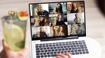 A person is holding a drink during a video call with friends.