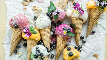 Eistüten liegen verstreut, geschmückt mit Beeren und Blumen.
