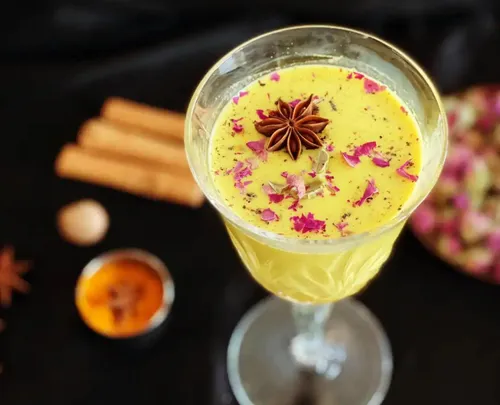 A drink with spices and flowers on a black background.