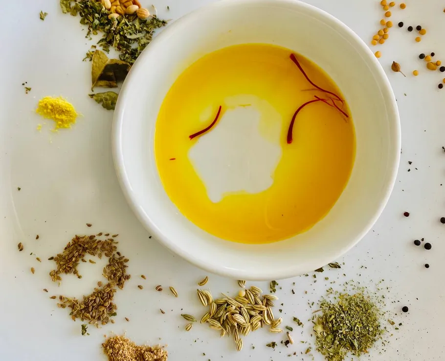 Schüssel mit Öl, Gewürzen und Safran im Hintergrund.