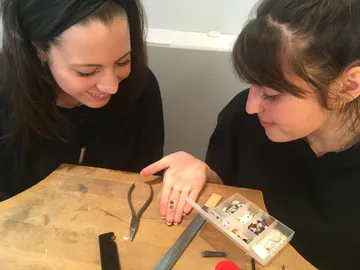 Zwei Frauen betrachten Schmucksteine auf einem Tisch.