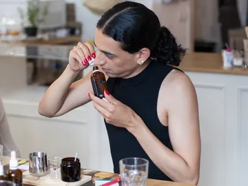 Eine Person riecht an einer Flasche in einem Café.