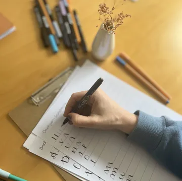 A hand writes on paper with a pen.