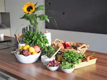 Vegetables and fruits on a kitchen table in a bright room.