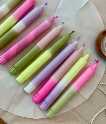 Bunte Kerzen liegen auf einem Tisch mit Papier.