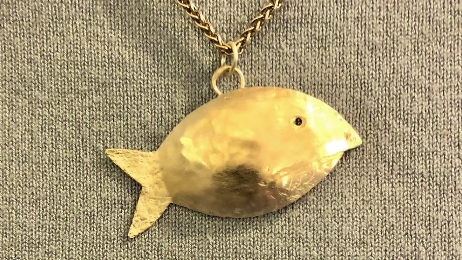 Goldener fischförmiger Anhänger an der Kette.