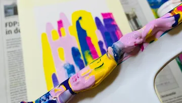 Bunt gestrichene Palette neben einem unvollendeten Kunstwerk.