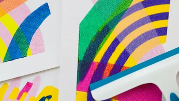 Bunte Farben werden mit einem Werkzeug auf Papier verteilt.