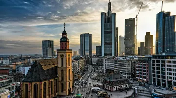 Modern high-rise buildings surround an old church at sunset.