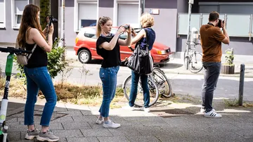 Four photographers take pictures on the street.