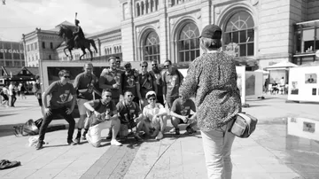 A woman photographs a group of men outside.