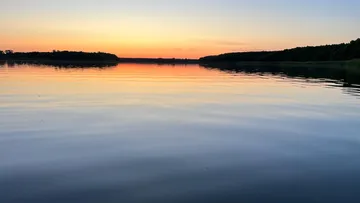 Ruhiger See spiegelt bunte Sonnenuntergangsfarben im Hintergrund wider.