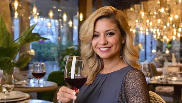 Smiling woman holding wine glass in restaurant.