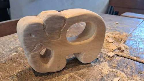Holz-Elefant steht auf einem Tisch, umgeben von Spänen.