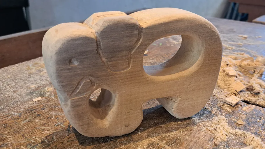 Holz-Elefant steht auf einem Tisch, umgeben von Spänen.