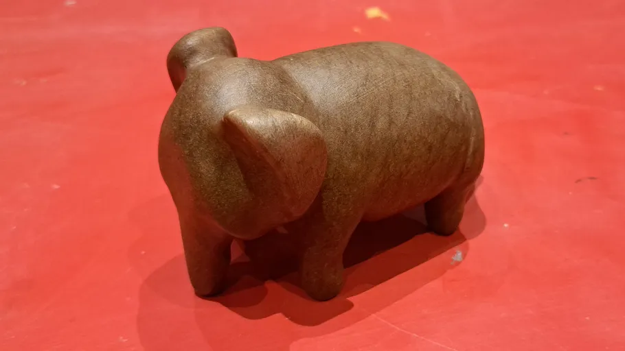 Carved wooden elephant on red surface.