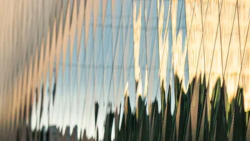 Reflektierende Wand verzerrt Himmel und Umgebung in der Nähe.