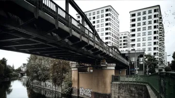 Brücke verbindet Wohngebäude über ruhigen Fluss.
