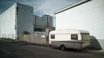 Ein Wohnwagen steht an einer grauen Wand in der Stadt.