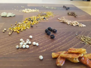 Verschiedene Gewürze liegen ausgebreitet auf einem Holztisch.