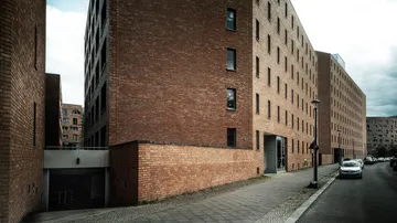 Ziegelgebäude stehen; Straße daneben; bewölkter Himmel.