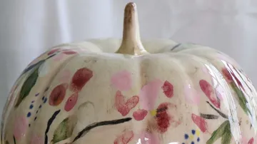 A painted pumpkin decoration is on a table.