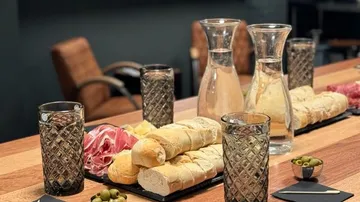 Table covered with bread, water, olives and glasses.