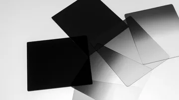 Dark, transparent plates lie chaotically on a surface.