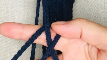 Dunkelblauer Faden wird von Hand gehalten und sortiert.