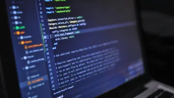 Laptop shows code on screen in a development environment.