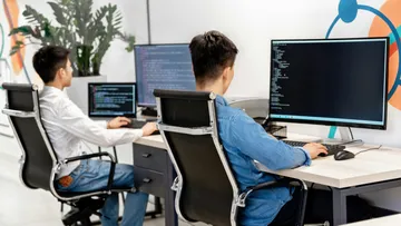 Two people work on computers in a modern office.