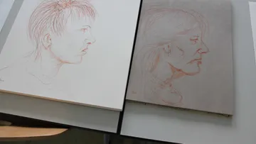 Two portraits in profile view are lying on a table.