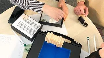 Holzobjekt wird auf einem Tisch untersucht, umgeben von Materialien.