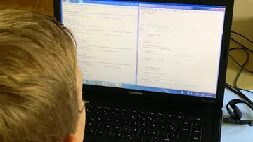 Person looking at code on laptop screen in the interior.