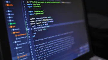 Code on a laptop is edited by a programmer.