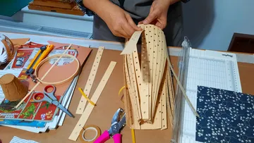Hands form a paper structure on a table.