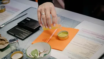 Eine Hand gießt Flüssigkeit in eine kleine Dose.