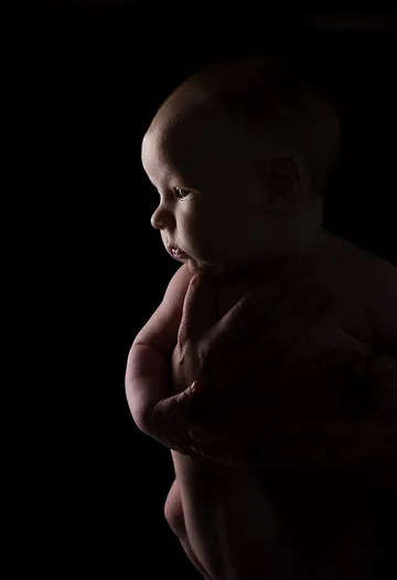 Baby in hand, looking thoughtfully at the darkness.
