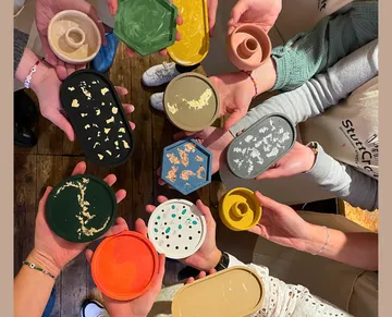 Mehrere Hände halten bunte Schalen in einem rustikalen Raum.