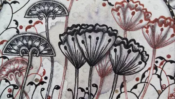 Schwarze und rote Blumen wachsen auf hellem Hintergrund.