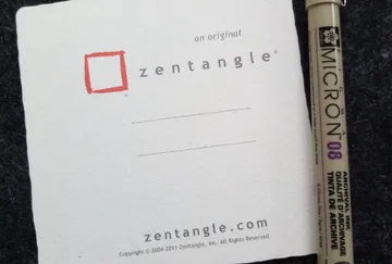 Zettel und Stift liegen auf einem dunklen Untergrund.