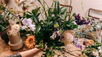A bouquet of colorful flowers is kept surrounded by other plants.