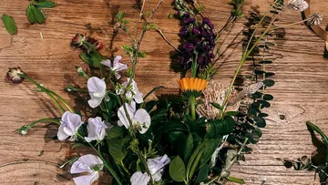 Colourful flowers and leaves lie on a wooden background.